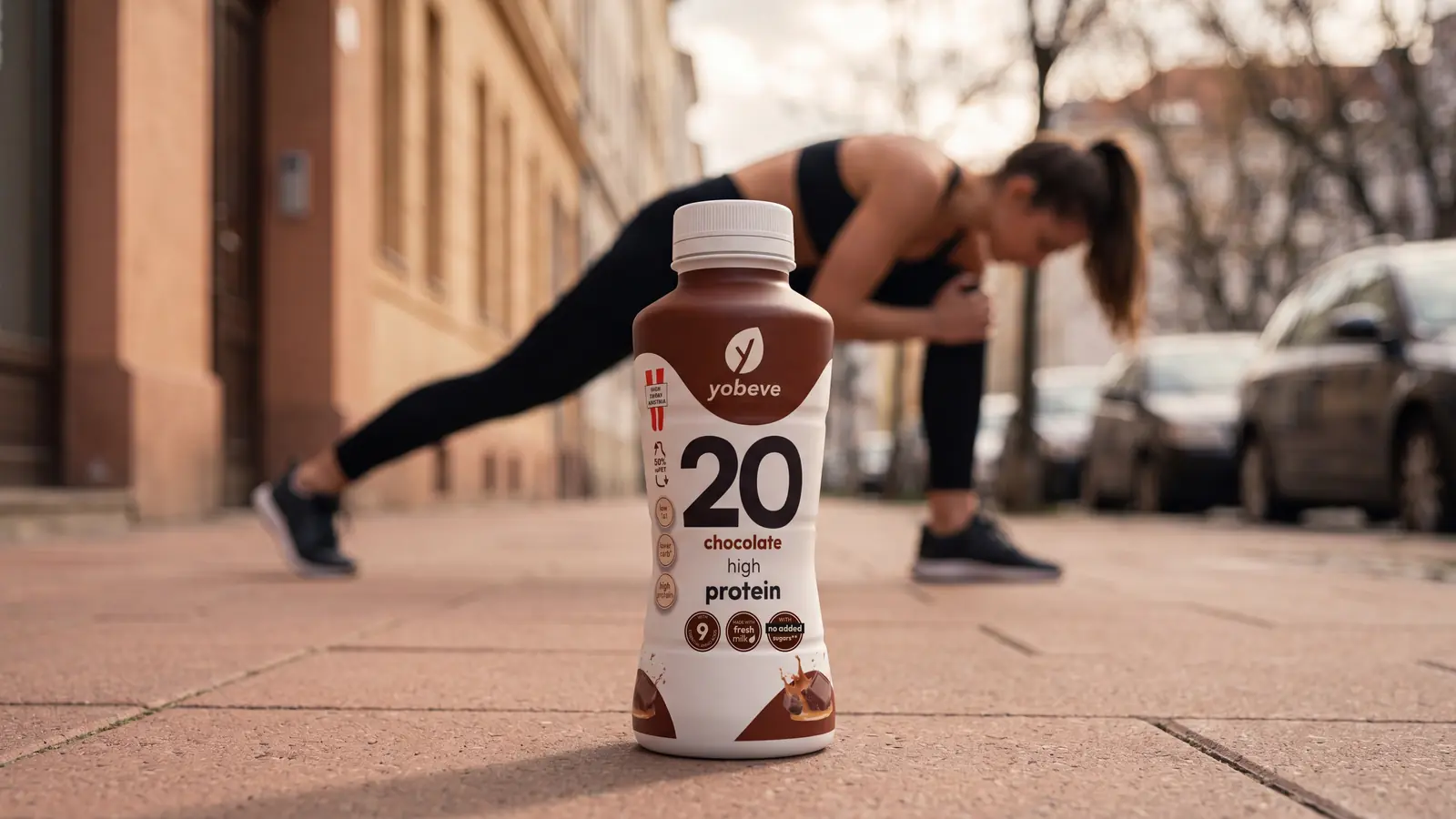 Chai protein drink chocolate yobeve ở phía trước khi người tập giãn cơ ngoài trời
